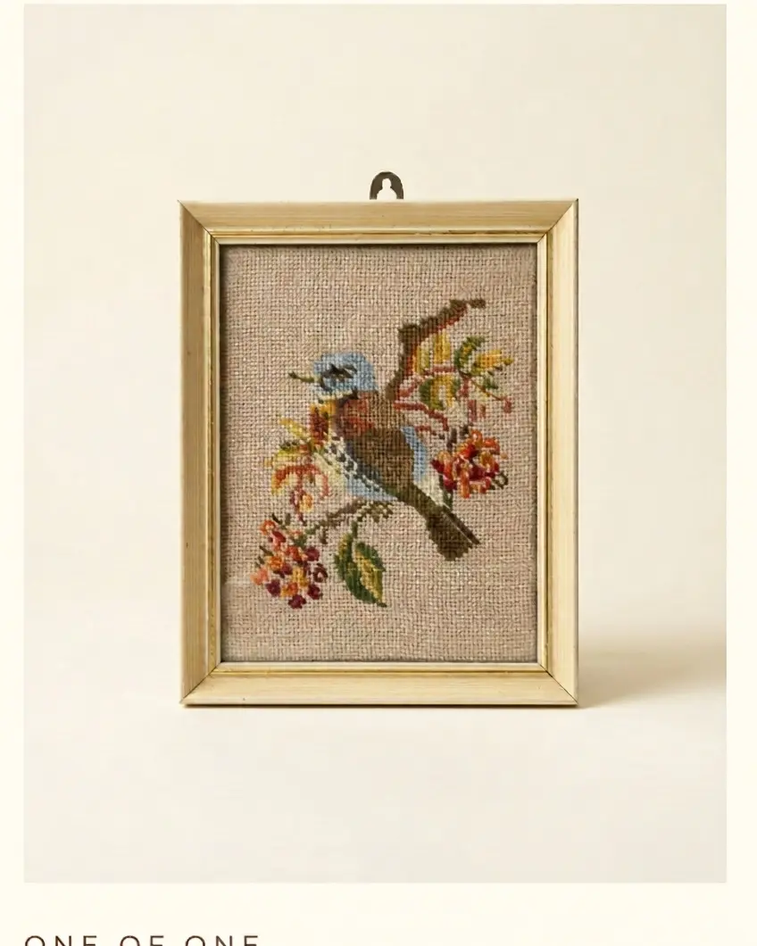 A small gilt framed needlepoint tapestry of a bird among flowers
