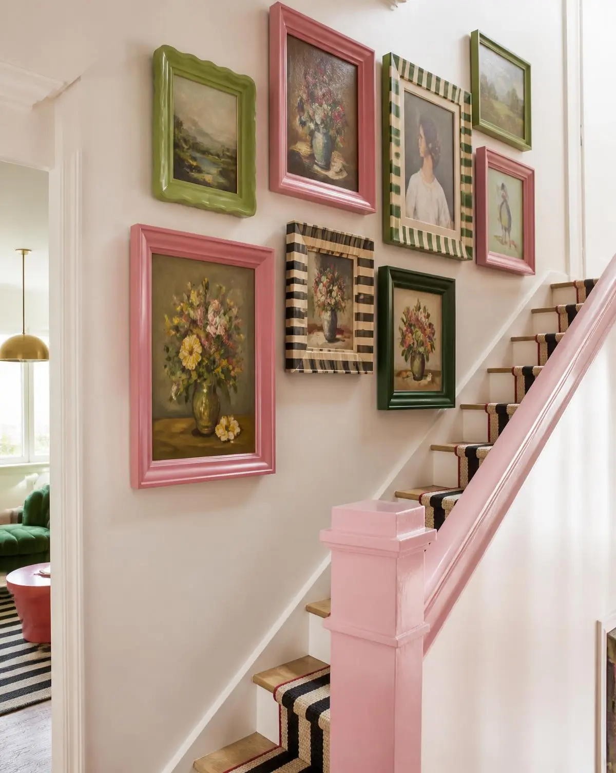 Vintage paintings in pink, green and striped frames climbing a staircase wall
